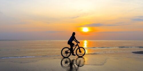 woman bike riding on beach