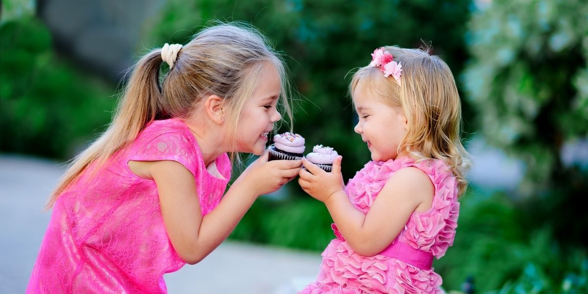two little girls happy eating cupcakes